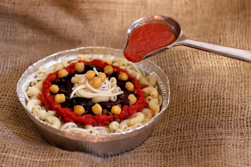 Le koshari avec sa sauce et ses oignons frits, et une assiette de foul medammes.